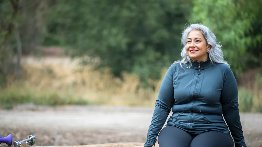 A Hispanic Woman Sits on a Log, Taking a Break From a Hike