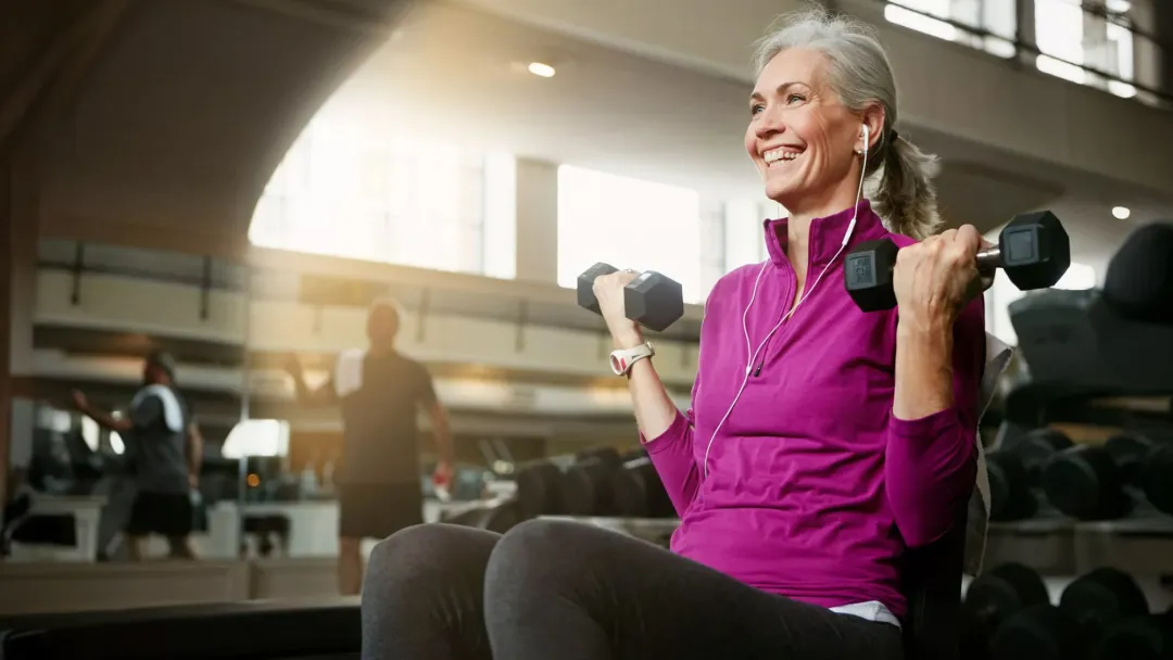 Elderly Woman lifting weights at a gym