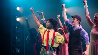 A group of young people raising their fists on a stage.