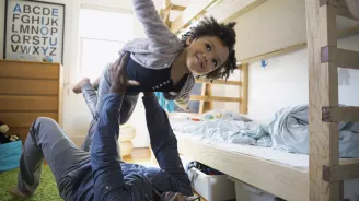 Father and child playing airplane in a kid's bedroom