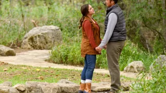 Couple standing and holding hands on a path in the forest.