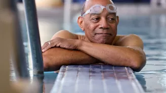 Elderly black man with goggles in a swiming pool.