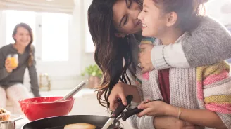 A woman hugging her daughter in the kitchen.