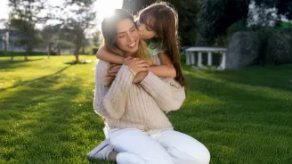 Mother and daughter embracing in yard