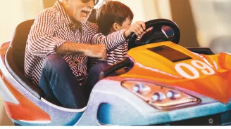 Grandfather and grandson playing in a bumper car
