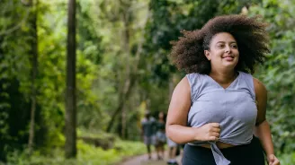 Hispanic woman running outdoors in a forest.