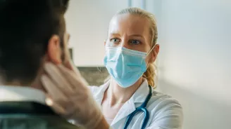 Masked physician examining patient.