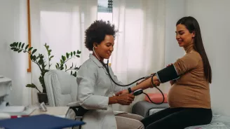 Pregnant woman getting her blood pressure checked by a physician.