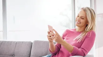 Woman sitting on a couch using a smartphone.