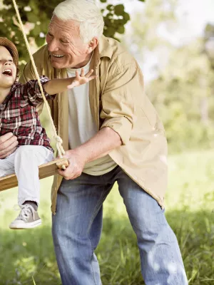 Grandfather pushes grandson on a tree swing