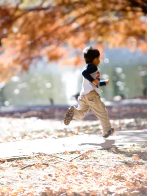 A small boy runs beneath the autumn leaves