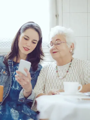 A young woman with an older women checking a cell phone