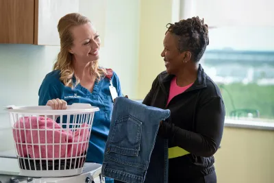 A female patient folds laundry with a rehab specialist.