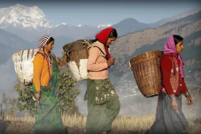 International women walking with baskets on their backs.