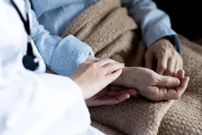 Close up of a physician's and hospice patient's hands.