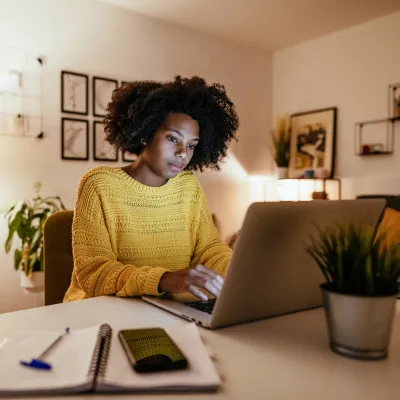 Woman looking at her laptop screen in a home office in the evening