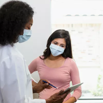 Female doctor goes over a medical chart with a female patient.