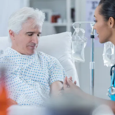 A Patient Lays on an Exam Table as a Nurse Inserts a PICC line
