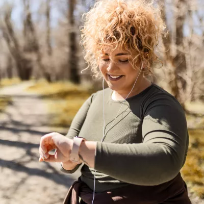 A Woman Checks Her Smart Watch While Going For a Run in the Park