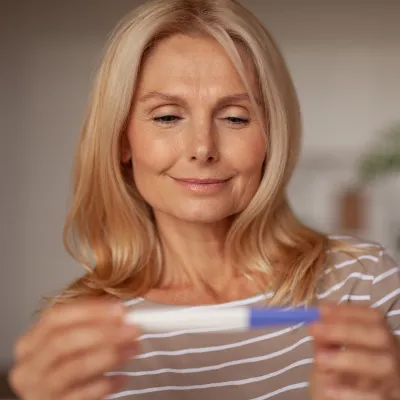 A Woman Smiles as She Looks at a Pregnancy Test