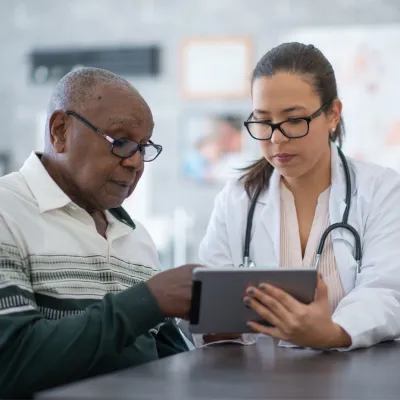 A Provider Goes Over a Patient's Chart with Him on a Tablet.