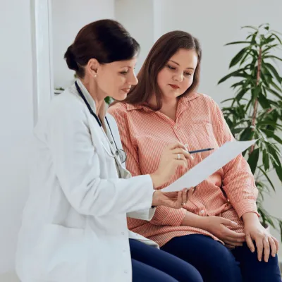 Female Doctor talking to Female Patient Showing Her Paper