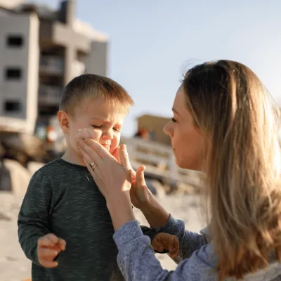 Mother putting sunscreen on chiild