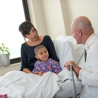 A child patient sits with his mom and smiles at his doctor.