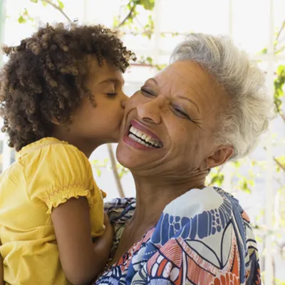 A grandmother receives a kiss on the cheek from her granddaughter.