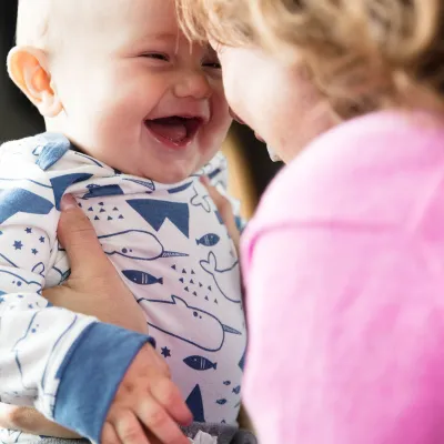 Baby laughing while his mother is holding him.