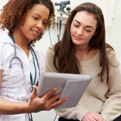 A nurse shows a young woman her test results from a prevenetive screening.