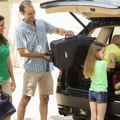A family packs their car full of luggage.