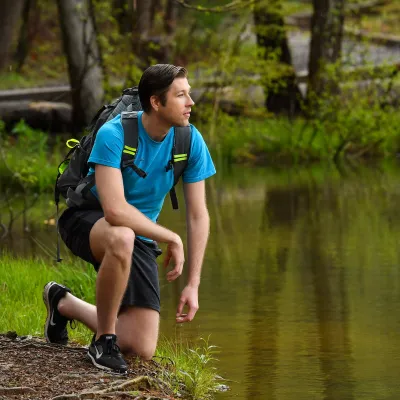 Taking a rest near a lake while hiking through the woods.