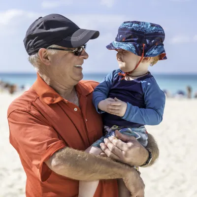 A grandfather and grandson practice sun safety at the beach.