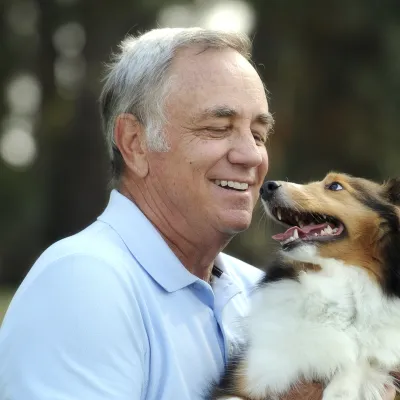 A Caucasian man plays with his pet Collie dog.