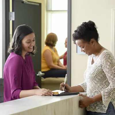 A female patient fills out paperwork for her doctor appointment.