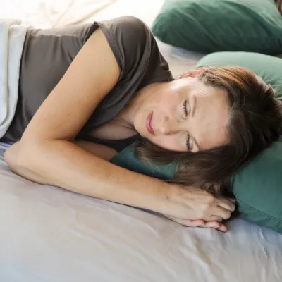 A woman sleeps soundly on her side in bed