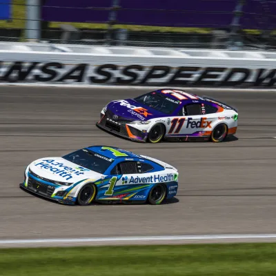 AdventHealth and FedEx NASCAR cars next each other while racing at Kansas Speedway.