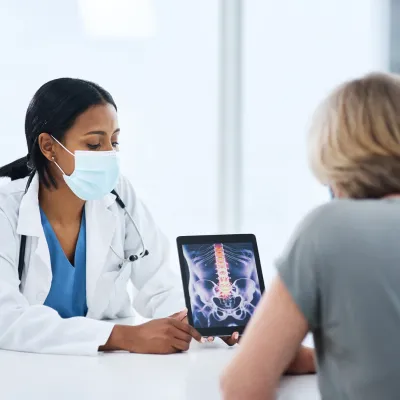 Physician with patient reviewing lower spine on tablet