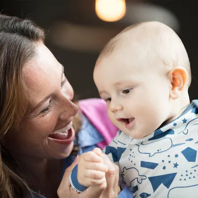 Baby standing held by Mama.