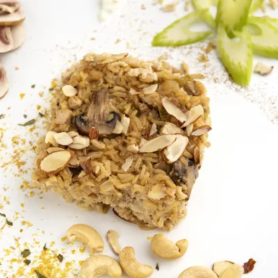 Square of almond chick'n rice on white surface with mushroom decoration
