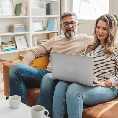 Couple looking at laptop togeter on couch. 