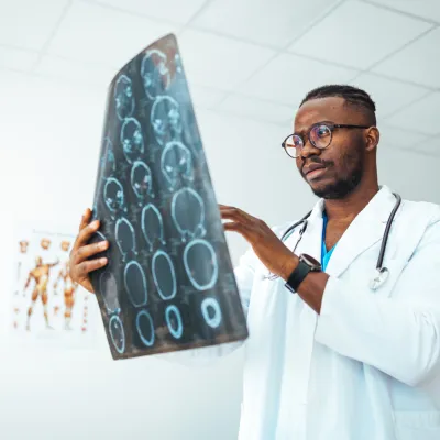 A male doctor holds up a sheet of brain scan images