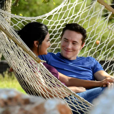 Couple sitting on a hammock outside.