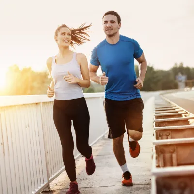 A Young Couple jogging at sunset by a road