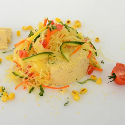 Mound of mascarpone polenta with squash ribbon spaghetti and vegetable garnish
