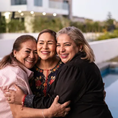 Female Latin friends hugging each other and laughing at home