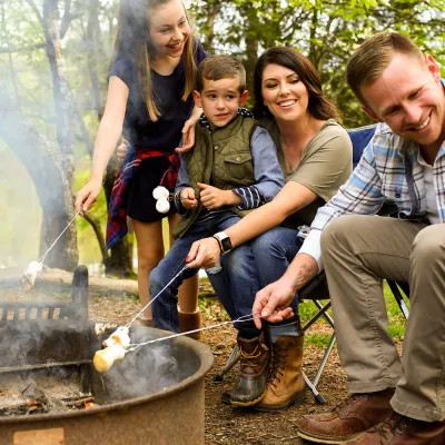 Family sitting around campfire and cooking smores