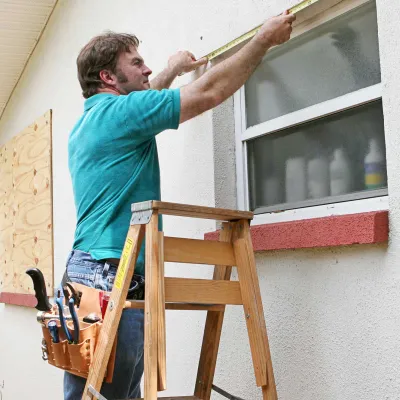 A journeyman measuring a window of a house