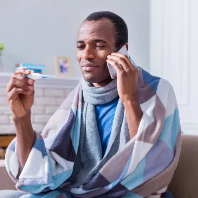 A man with a fever calling his doctor from home.